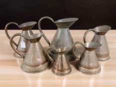 A graduated group of six copper jugs, tallest 36 cm.