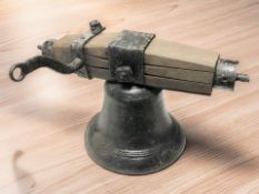 A cast iron bell with wooden and wrought iron hanger, overall width 50 cm.