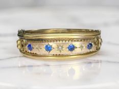 A Victorian 9ct gold diamond and synthetic sapphire hinged bangle, inner width 5.