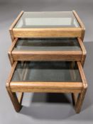 A teak and smoked glass nest of three tables, width 50 cm.