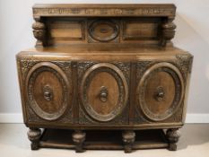 A 1920's heavily carved oak bow front triple door sideboard, 150 cm x 60 cm x 141 cm.