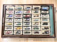 A glazed pine counter top display cabinet containing a collection of boxed die cast vehicles