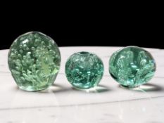 Three Victorian Sunderland green glass dumps with bubble inclusions, tallest 12 cm.