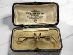 A 9ct gold fox and riding crop brooch, with ruby-set eyes, width 5.