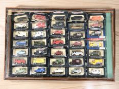 A glazed pine counter top display cabinet containing a collection of boxed die cast vehicles