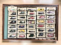 A glazed pine counter top display cabinet containing a collection of boxed die cast vehicles