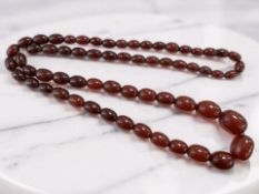 A cherry amber/Bakelite bead necklace, the graduated oval beads ranging in width from 23mm to 11mm,