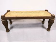 A teak and cane window seat, length 124 cm.