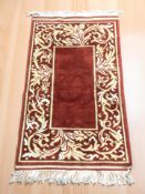An oriental fringed rug on red ground, 143 cm x 80 cm.