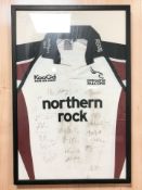A Newcastle Falcons Northern Rock rugby shirt with team signatures, in frame.