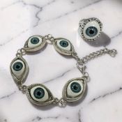 A white metal earring and bracelet suite set with simulated eyes.