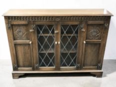 A 20th century carved oak bookcase with leaded glass doors, 135 cm x 29 cm x 100 cm.