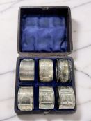 Two silver napkin rings, and a set of four plated napkin rings in the form of belts, cased.