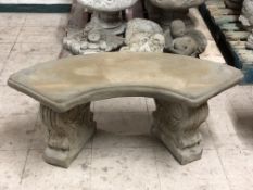 A curved concrete garden bench,