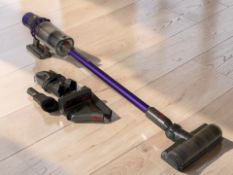 A Dyson Cyclone stick vacuum cleaner with lead and attachments.