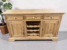 A contemporary pine sideboard with central bottle rack, 153 cm x 41 cm x 92 cm.