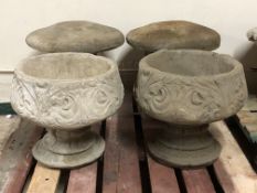 A pair of concrete garden urns on pedestals,