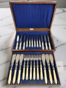 A walnut canteen containing a twelve place setting of EPNS fish cutlery, with faux ivory handles.