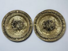 Two large embossed brass chargers depicting continental tavern scenes, diameter 72 cm.