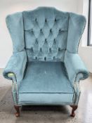 A reproduction wingback armchair in deep buttoned and studded blue upholstery, width 90 cm.