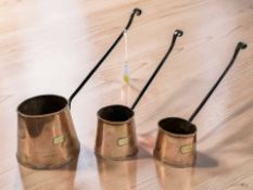 A set of three brass cider measures, largest 35 cm long including handle.