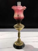 A Victorian brass oil lamp with canberry glass shade,