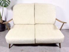 A 20th century Ercol stained beech two seater settee with cream floral cushions, width 135 cm.