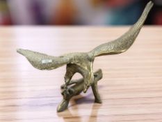 A large cast brass figure of an eagle perched on wooden branch, width 68 cm.