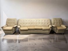 A 1960's teak framed and buttoned cream vinyl three piece lounge suite,