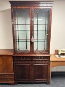 A reproduction mahogany double door bookcase with glass shelves internally, 99 cm x 40 cm x 214 cm.
