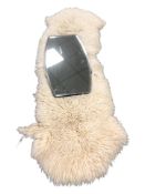 An Art Deco frameless mirror, width 69 cm, together with a sheepskin rug.