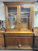 A reproduction cherry wood glazed double door bookcase, fitted cupboards beneath,