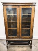 An Edwardian glazed oak double door bookcase on barley twist supports, 91 cm x 31 cm x 146 cm.