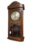 An early 20th century oak and beech wall clock, with pendulum and key.