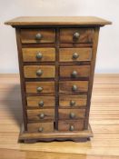 A miniature hardwood fourteen drawer chest, height 32 cm.