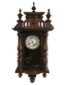An early 20th century beech Vienna wall clock with white enamel Roman dial, with pendulum,
