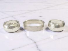 A hinged bangle, marks rubbed, together with two silver napkin rings.