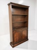 A reproduction mahogany open bookcase, fitted cupboards beneath, 102 cm x 32 cm x 184 cm.