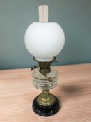 A Victorian brass oil lamp with clear glass reservoir and opaque shade,