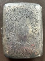 An Edwardian silver cigarette case engraved overall with scrolls and monogram, HM Chester 1904.