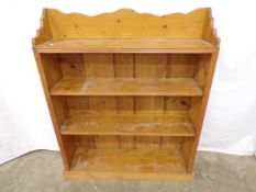 Pine open bookcase having shaped raised back over four shelves, standing on plinth base - 25cm x
