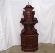 Hardwood corner cabinet having open shelf raised on carved pierced supports decorated with grapes on