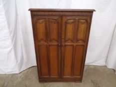 Oak linen fold tall boy having two panelled doors opening to a pull out hanging rail and three