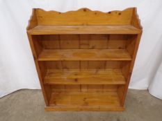 Pine open bookcase having shaped raised back over four shelves, standing on plinth base - 25cm x