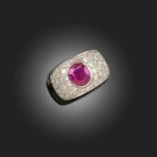 A RUBY AND DIAMOND BOMBÉ RING, the oval-shaped ruby within a surround pavé-set with single-cut