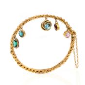 A GEM-SET HINGED GOLD BANGLE, of flattened curb-link design in yellow gold, suspending five