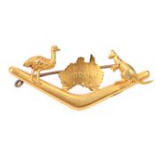 AN AUSTRALIAN YELLOW GOLD BROOCH, designed as a boomerang, surmounted with a motif of Australia