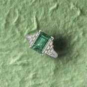 AN EMERALD AND DIAMOND RING, the step-cut emerald weighing 3.41cts with stepped shoulders set with