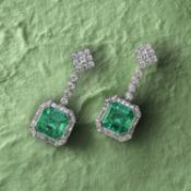 A PAIR OF EMERALD AND DIAMOND DROP EARRINGS, the step-cut emeralds weighing 2.20 and 2.45cts, within