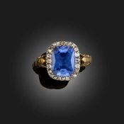 A SAPPHIRE AND DIAMOND CLUSTER RING, the cushion-shaped sapphire set within a surround of old